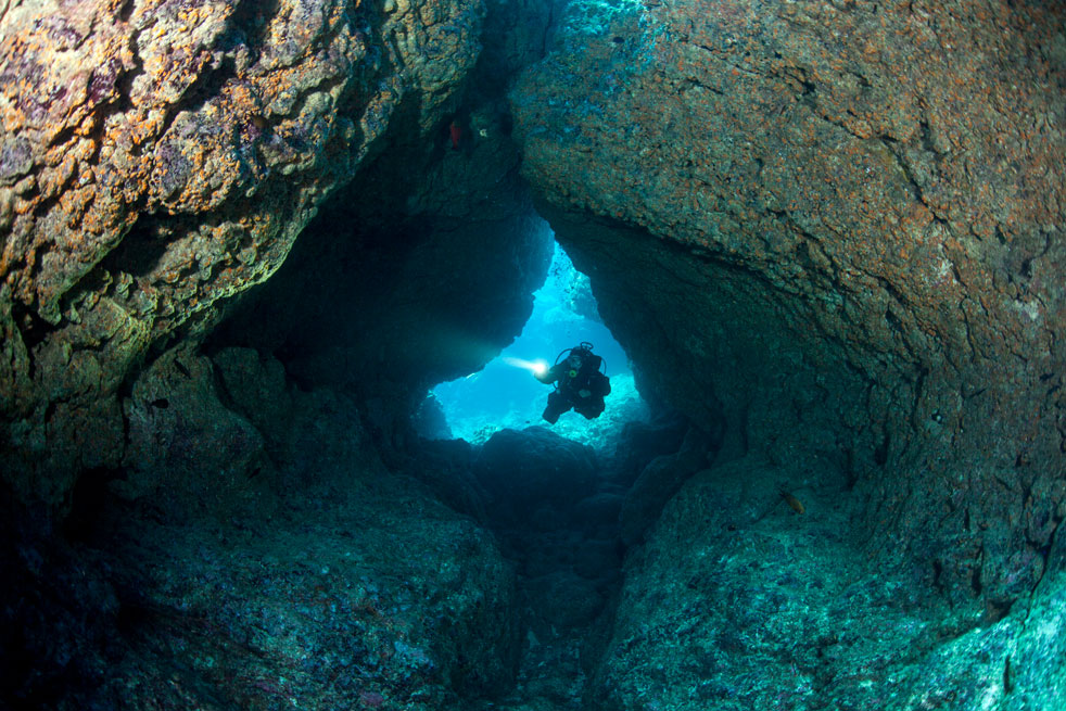 scuba-diver--enters-coral-cavern- cave diving - scuba diving - scubly
